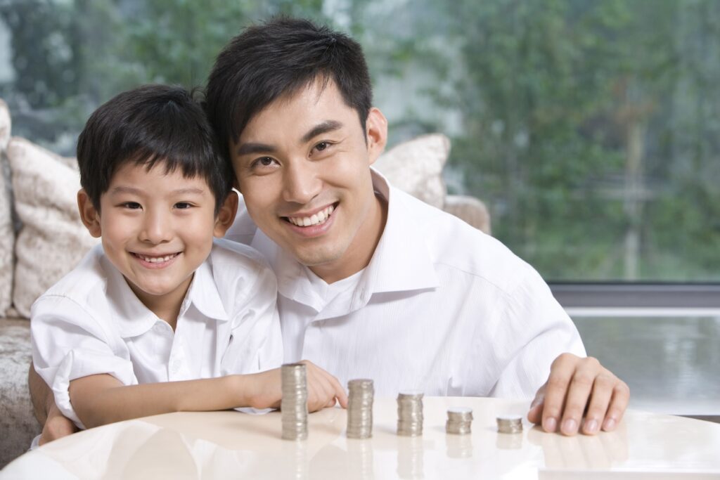 A father and son examining coins, representing the importance of financial security and the peace of mind that Singapore's Deposit Insurance Scheme provides.