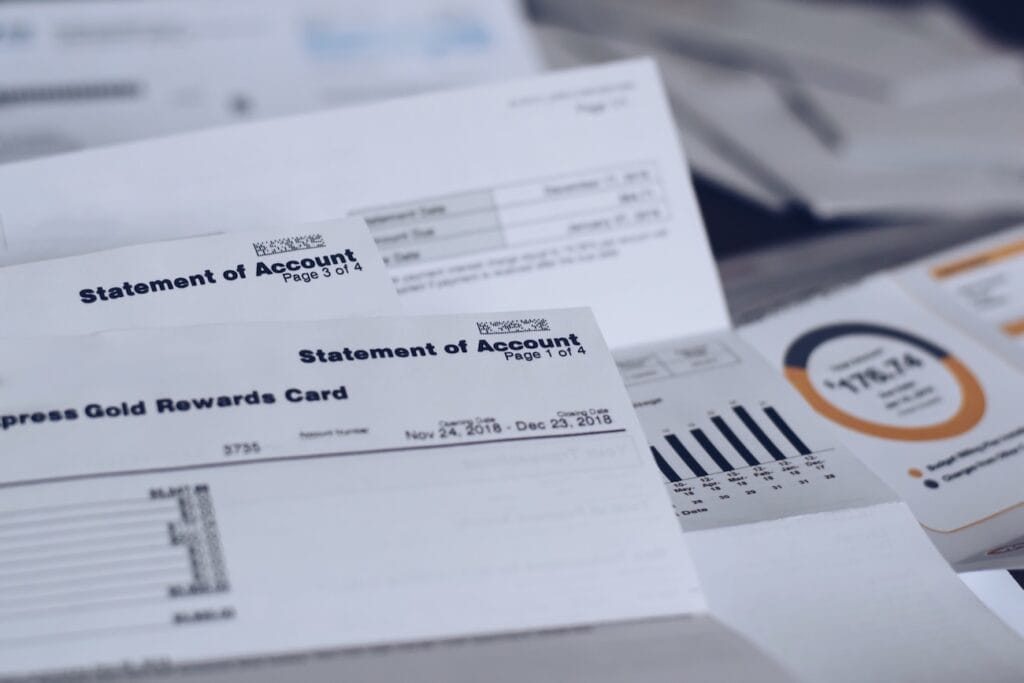 Close-up of various utility bills and a credit card spread out on a surface, representing the necessary documentation for opening a Swiss bank account.