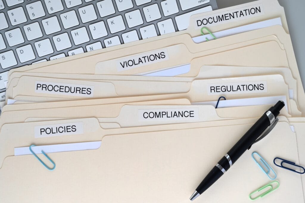 Folders labeled compliance, regulations, policies, and documentation representing requirements for how to open a bank account as a PEP