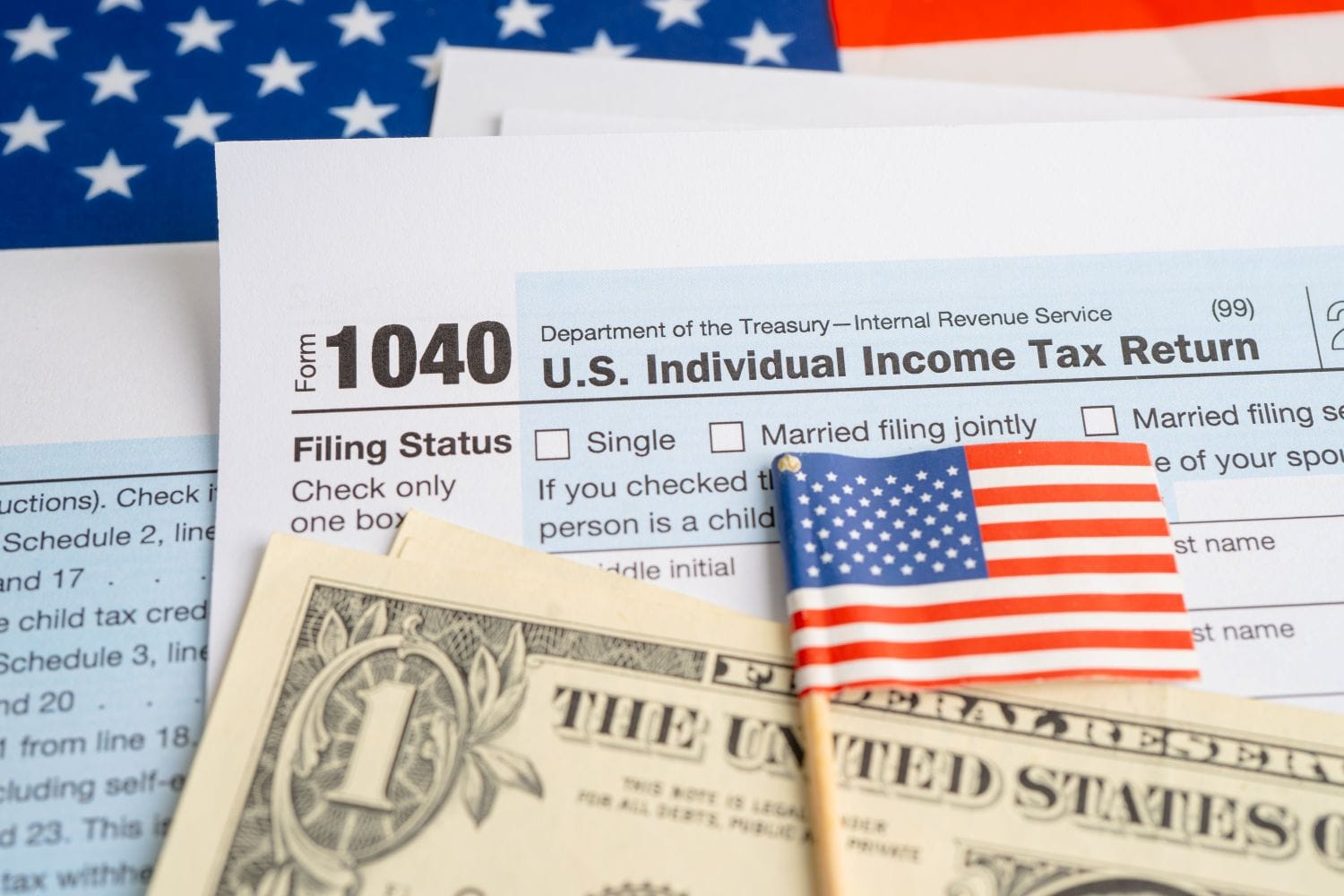US tax form 1040 with dollar bills and a small US flag representing US estate tax for foreign investors and asset classification.