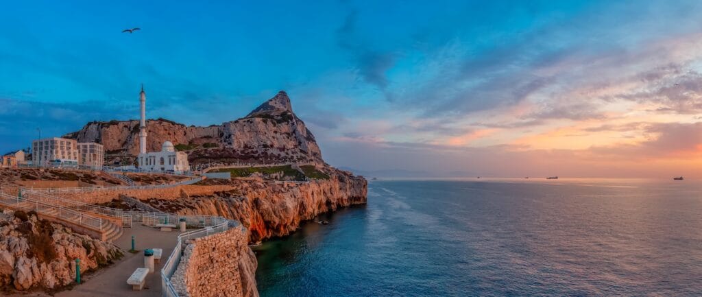 Europa Point Gibraltar at sunset with the Rock of Gibraltar and cargo ships on the Mediterranean — a key offshore corporate banking jurisdiction in 2026