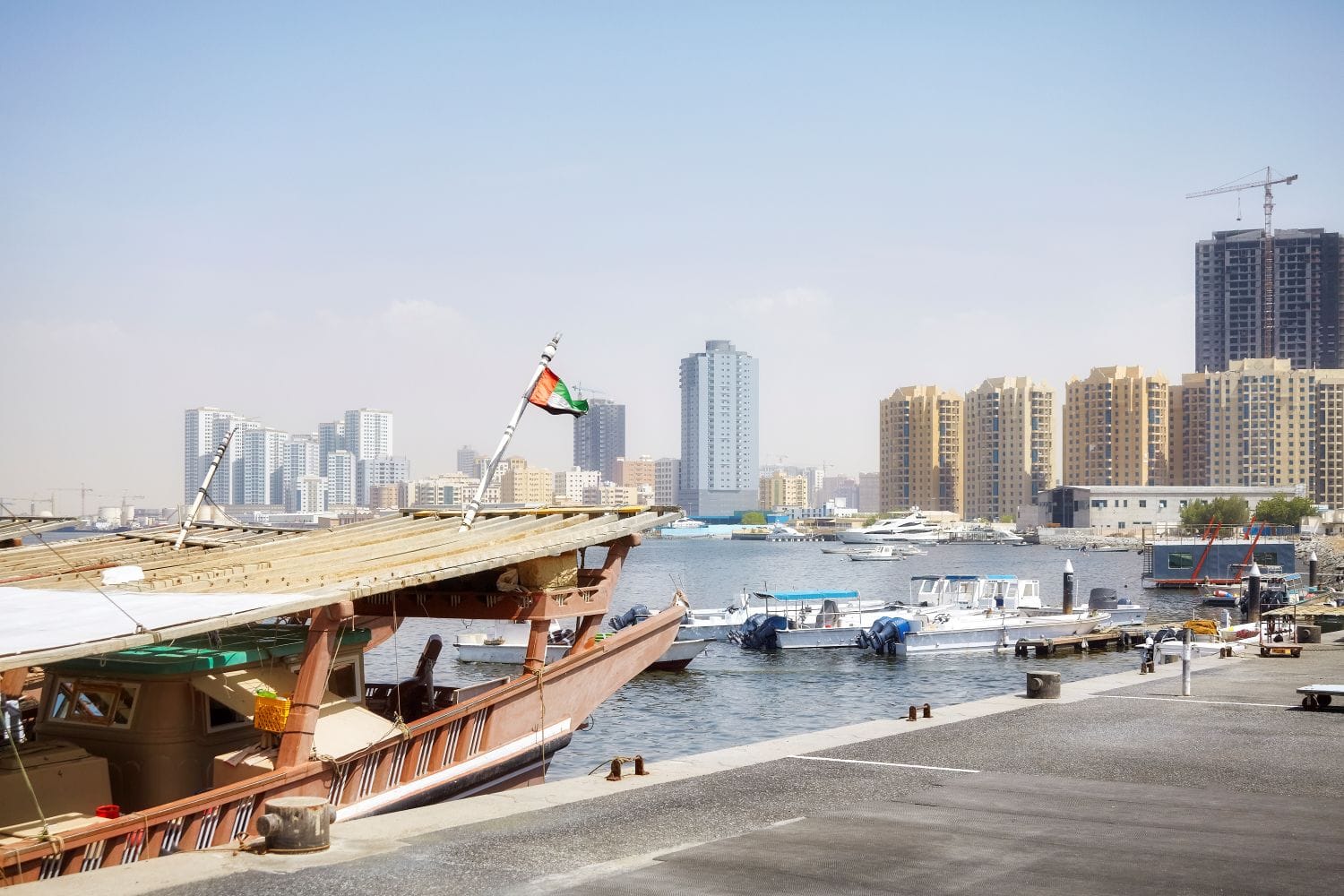 Traditional dhow boats at Ajman harbor with modern skyline in background, representing Swiss corporate account solutions for UAE freezone companies