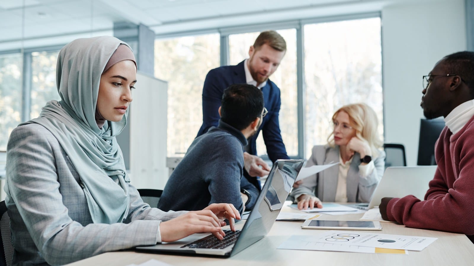 Diverse group of banking compliance professionals in a meeting reviewing documents, representing how a bank evaluates a new passport
