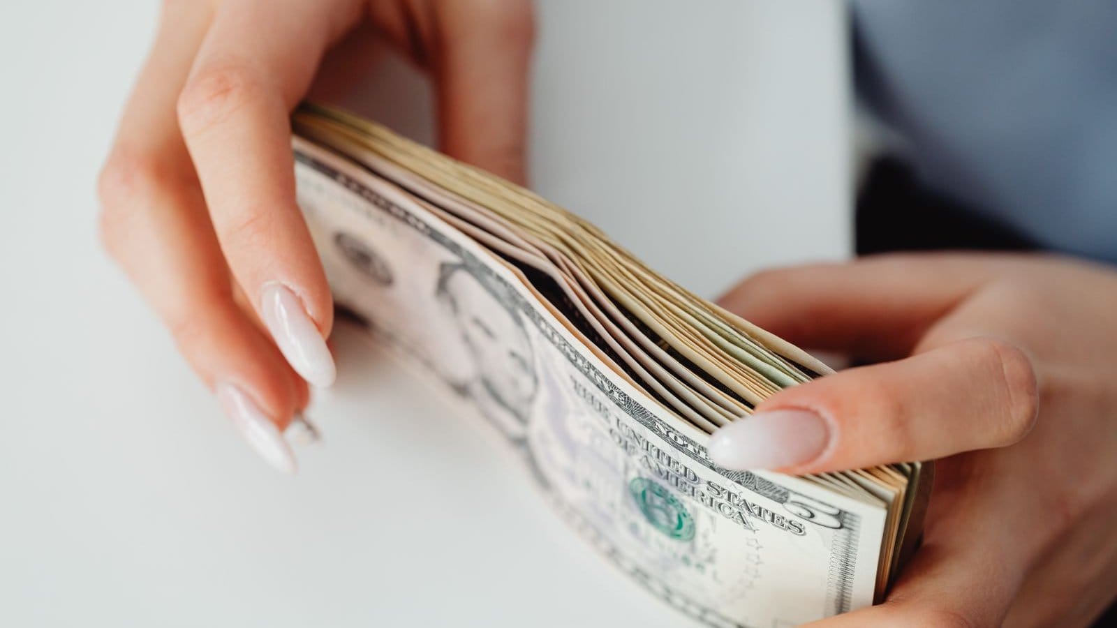 Remittance tax applies to cash: hands holding a stack of US dollar bills at a transfer counter